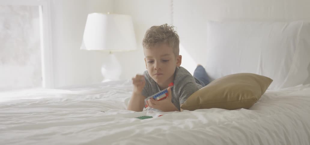 Child playing with a toy on a bed