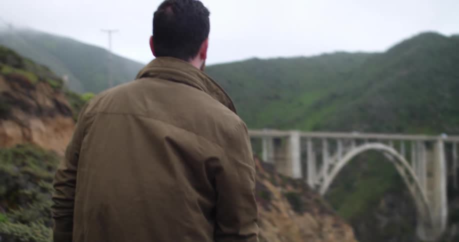 Man standing at a cliff checking his phone