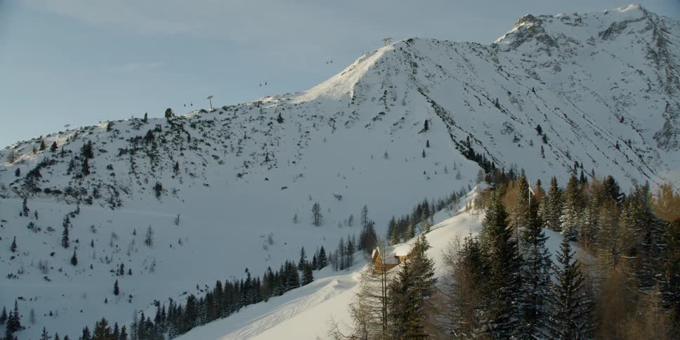 A moving chairlift on a snow covered mountain ridge