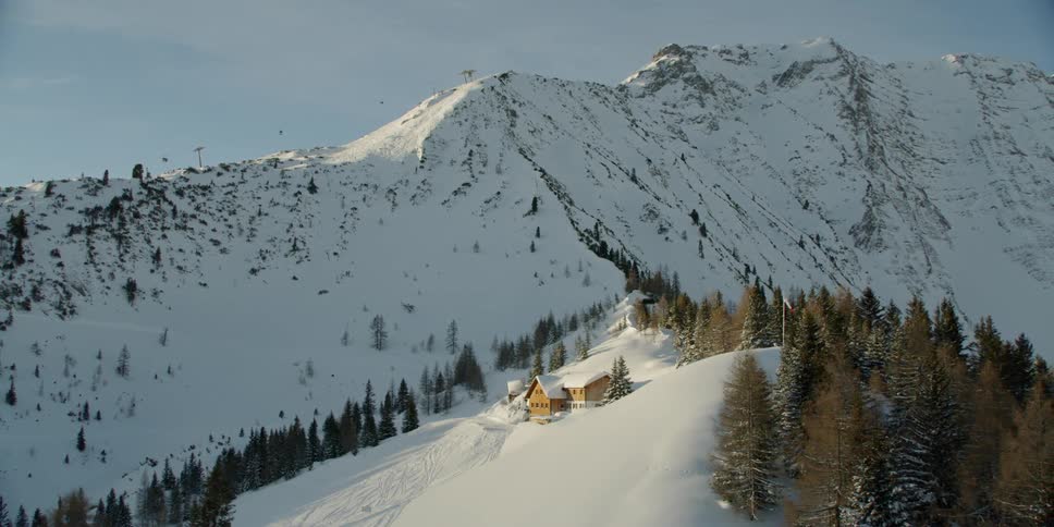 Building sits next to some trees on a snowy hill