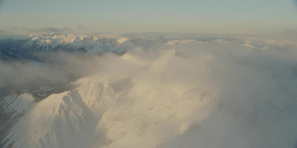 Mist hovers over a snow covered mountain