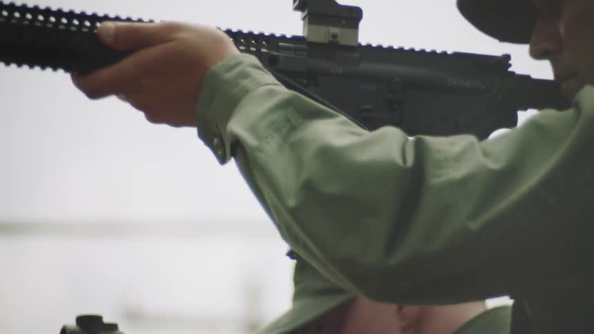 A soldier points his rifle aiming it