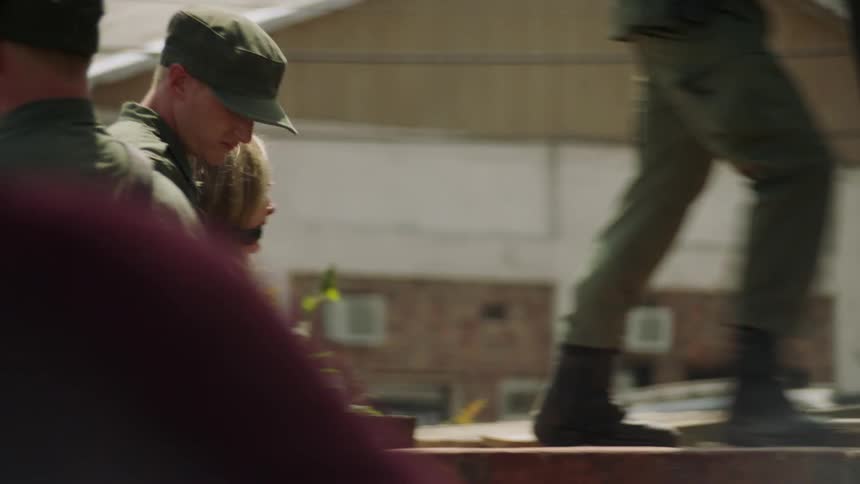 Soldiers march a man and woman up onto a platform
