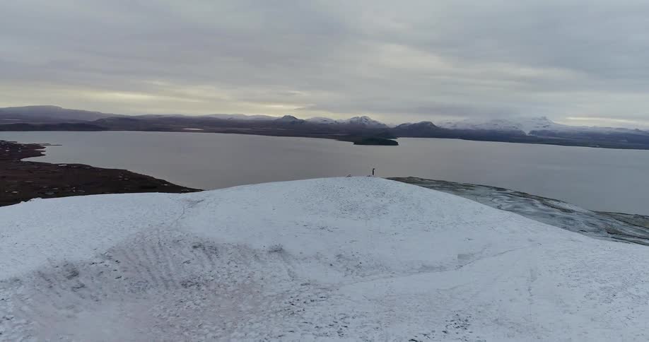 A hiker stands on a snowy mountain peak
