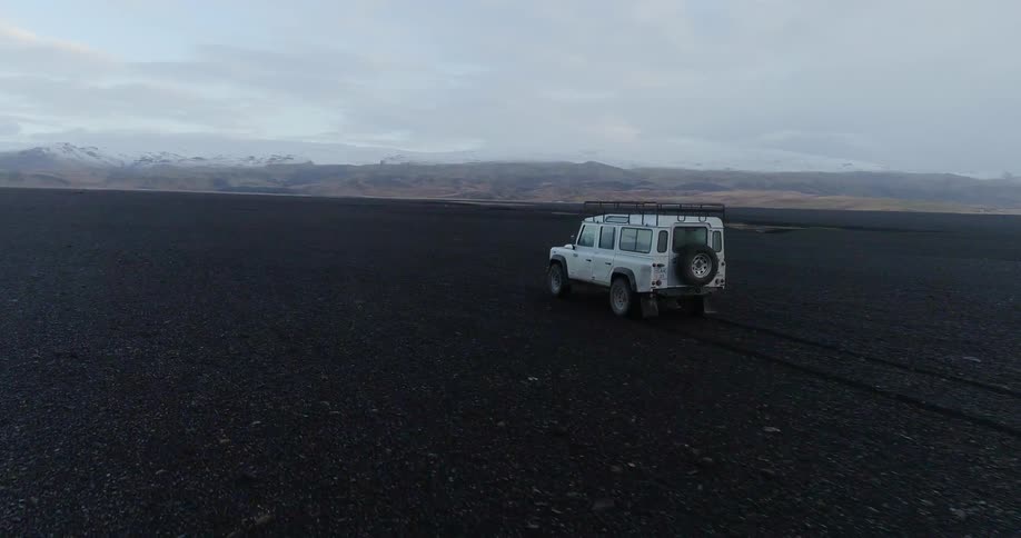 A vehicle drives across the long dark field