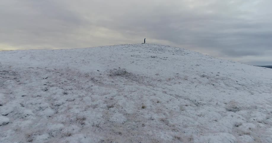 Man stands alone on a snowy hill