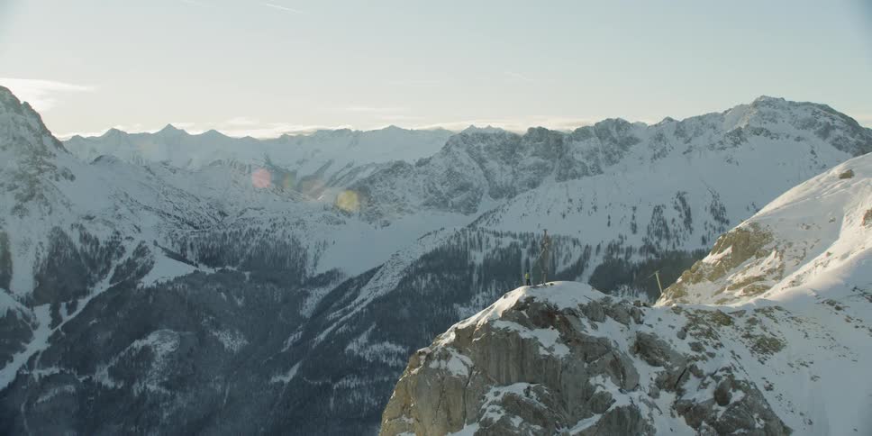 Person standing next to cross statue on top of snow covered mountain