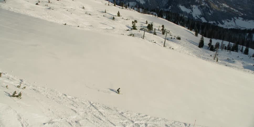 A person skis down a mountain slope on a sunny day