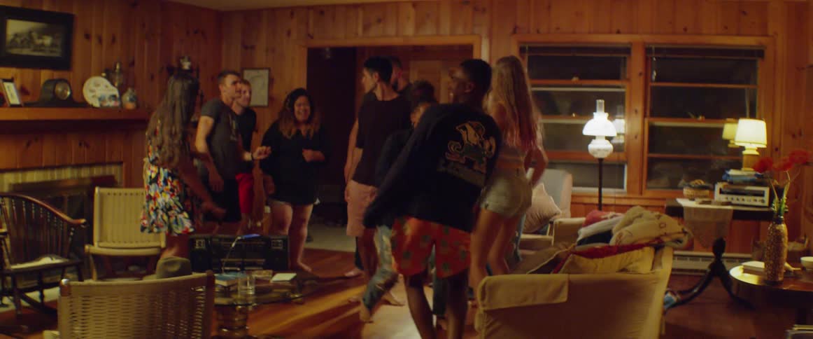 Group of men and women dance in a living room at night