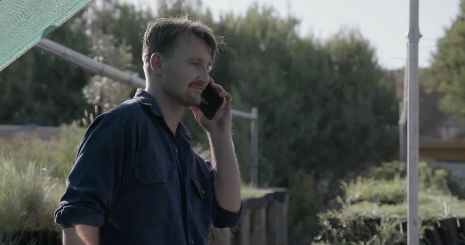 Man talks on his cellphone as he stands in a greenhouse