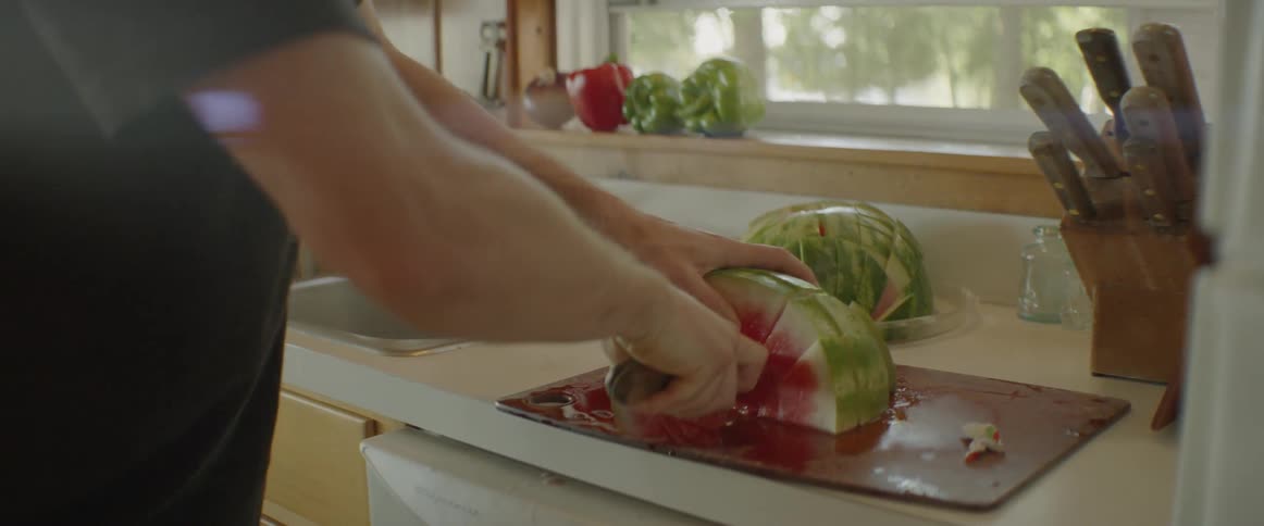 A man is cutting a piece of watermelon up