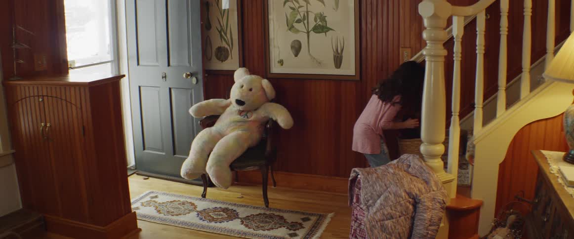 A young girl plays with a large stuffed bear