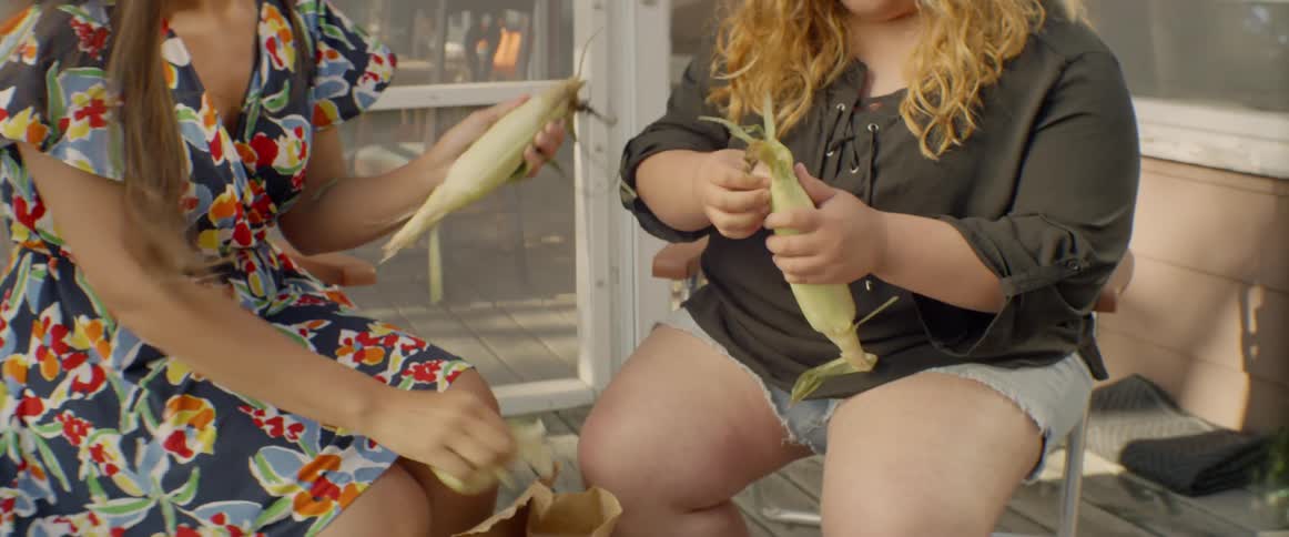 The women peel corn together in the yard