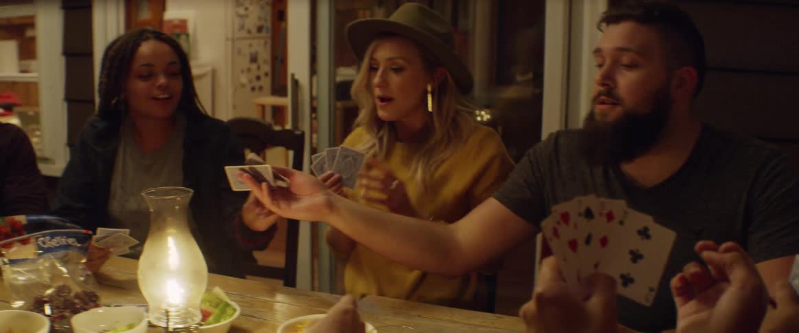 A group of people talk and play cards