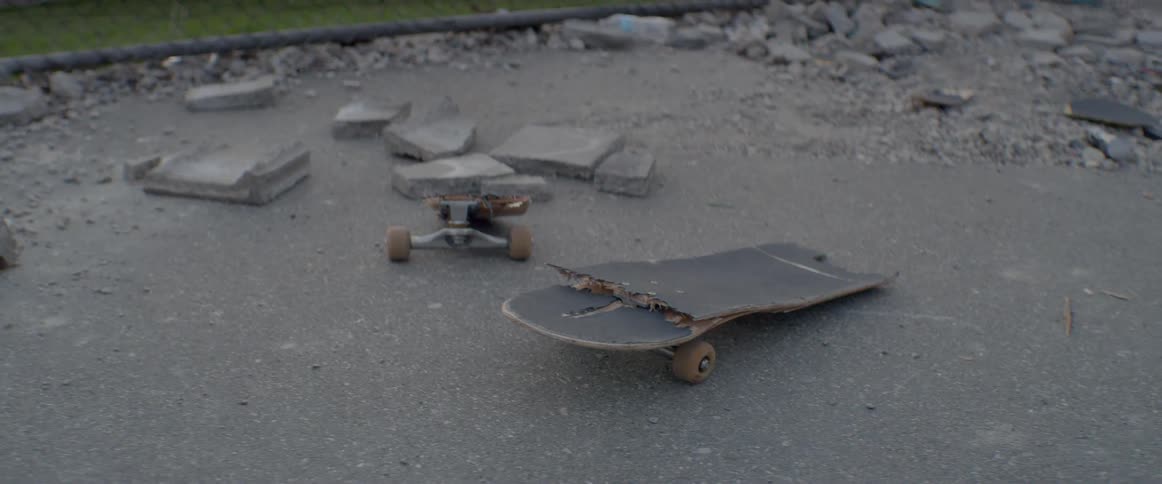 The skateboard is smashed apart in the lot