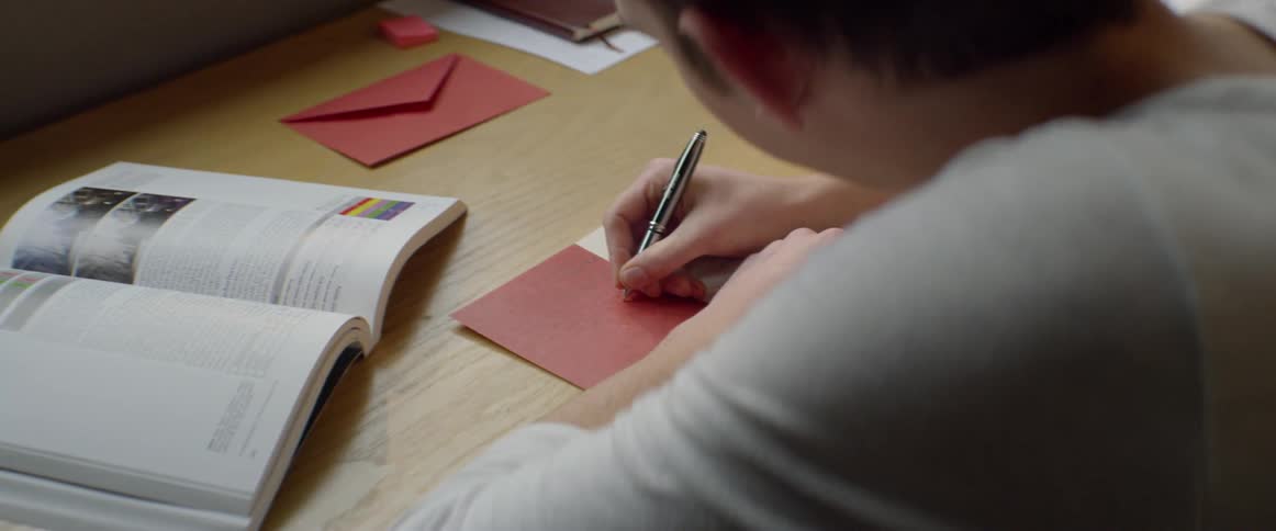 A person is writing in a greeting card