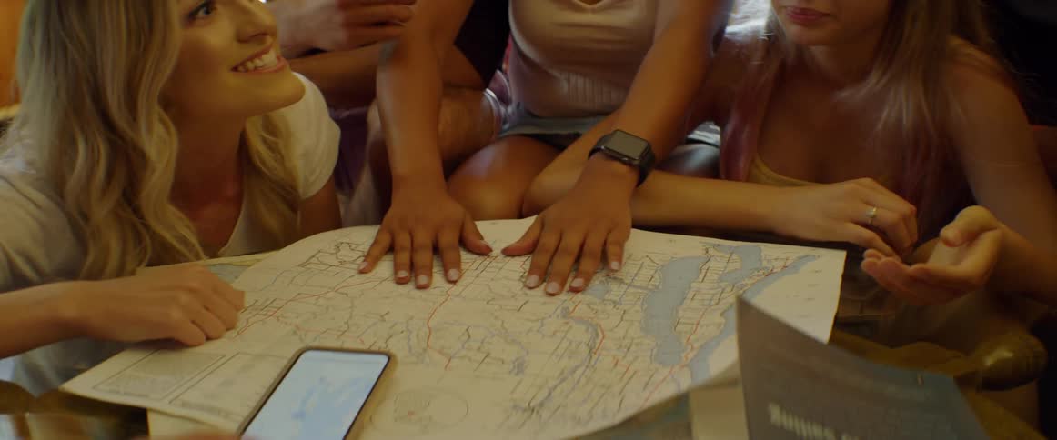 A group of friends are checking out a map and discussing it inside in daylight