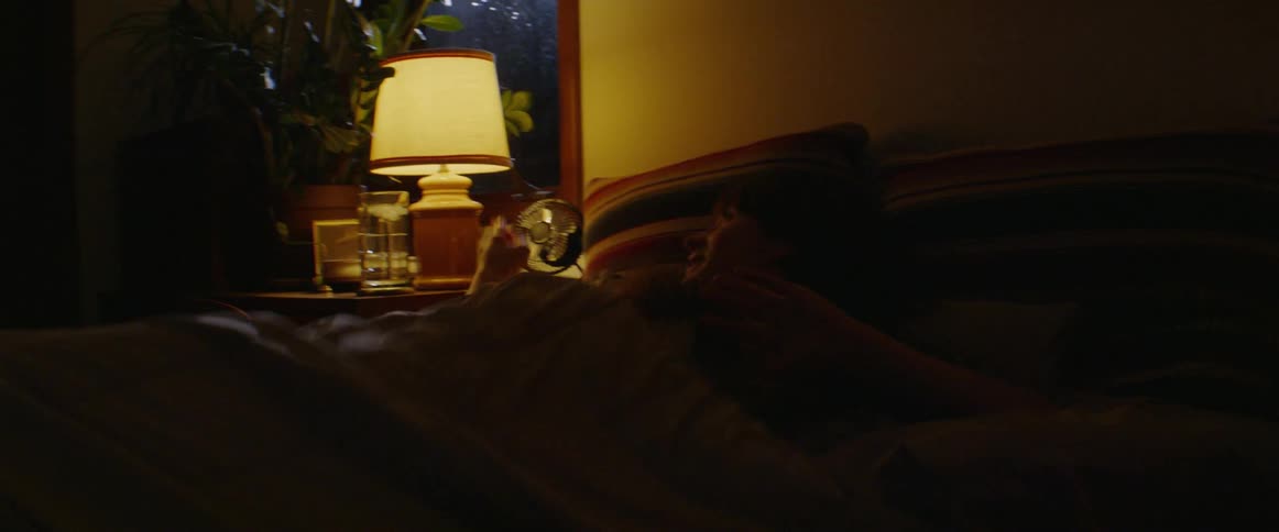 Woman laying in bed talking on her phone at night