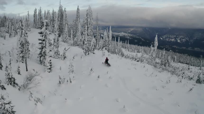 A person snowmobiles in snowy mountains