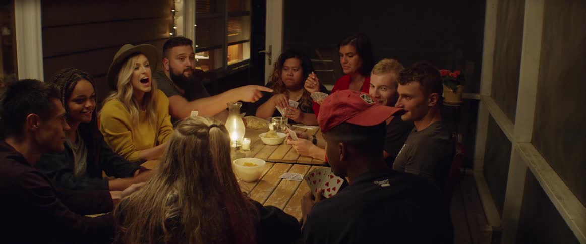 Group of people sit around a table playing cards