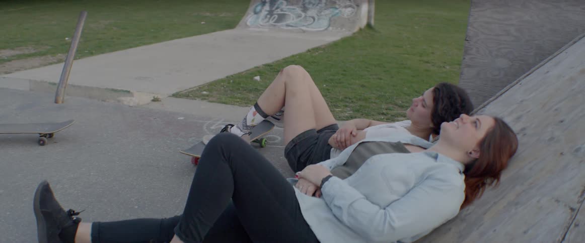 Two girls lean back against a ramp one skatepark