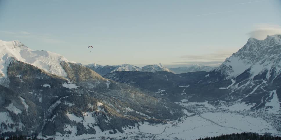 A person is paragliding over the mountains