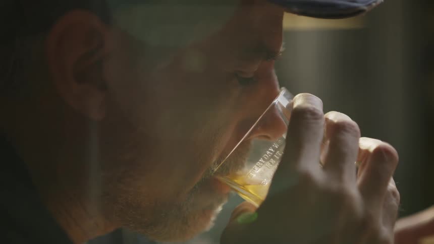 Man sips out of a glass of alcohol