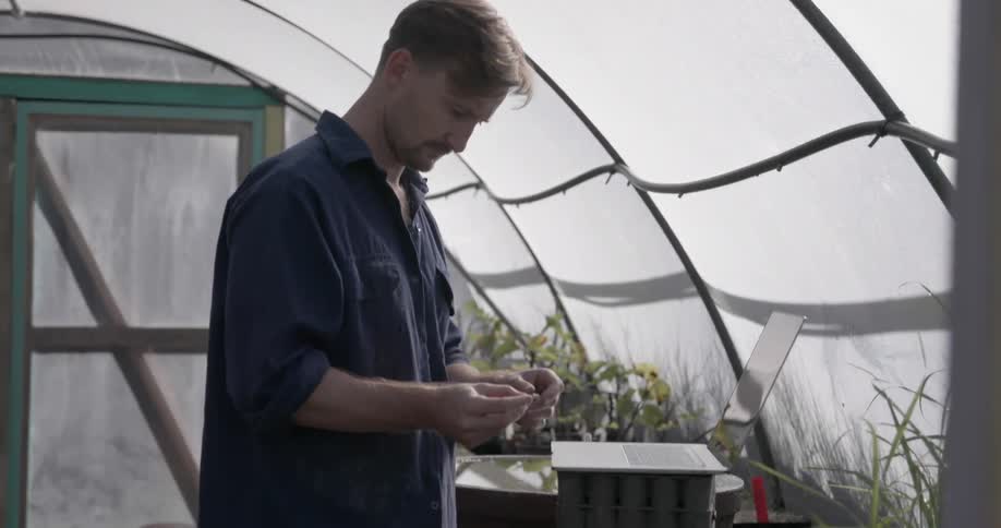 A man is planting things in his greenhouse
