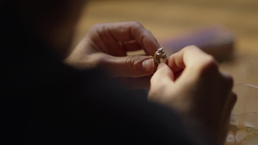A man holds a gold ring in his hands