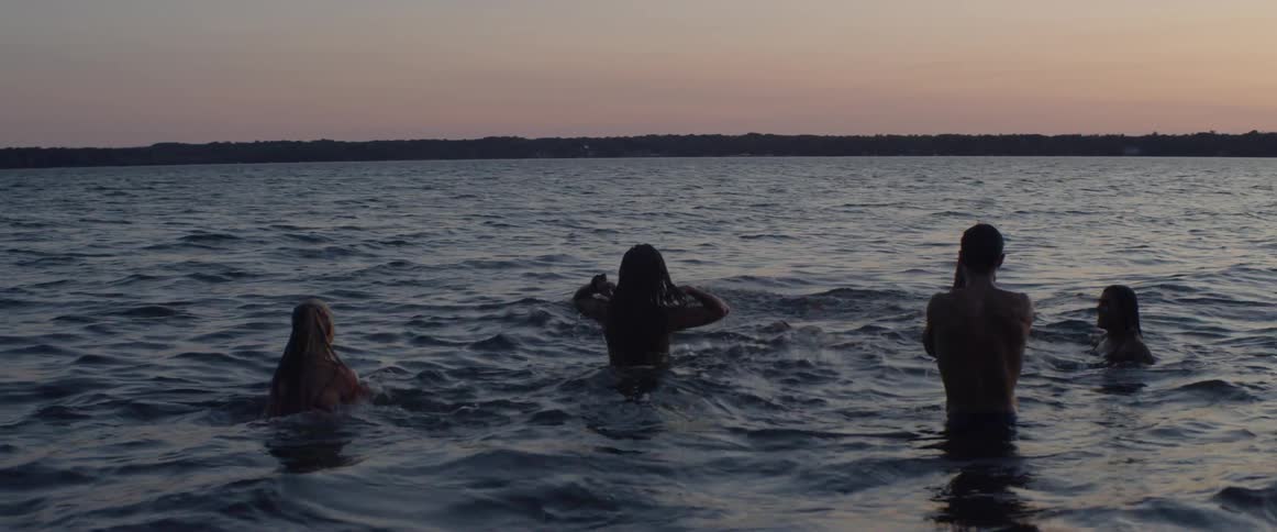 Group of men and women are dipping in lake water at sunset