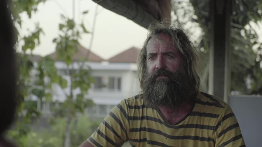 Man sits outside listening to another person talk