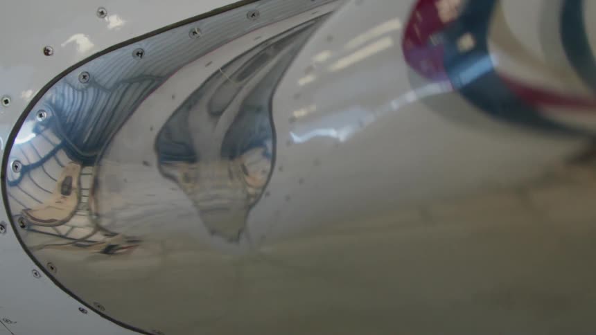 The surface of an airplane reflects the hangar it is parked in