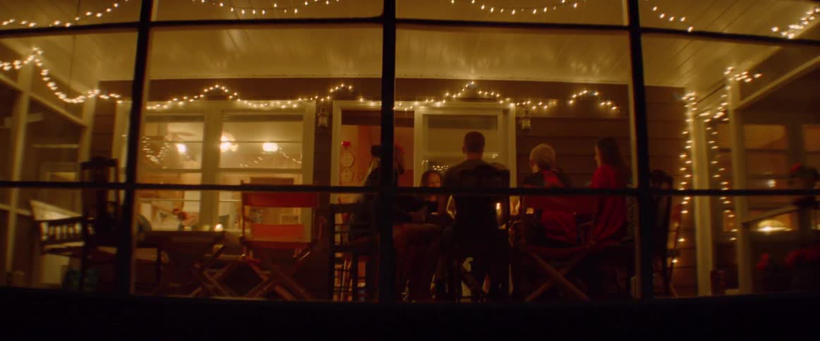 Group of people sit at a table in a room with large windows at night