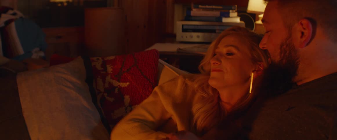 Man and woman sit on a couch cuddling at night