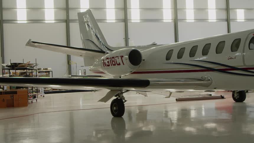 White airplane in a large airplane garage with sun shining through the windows