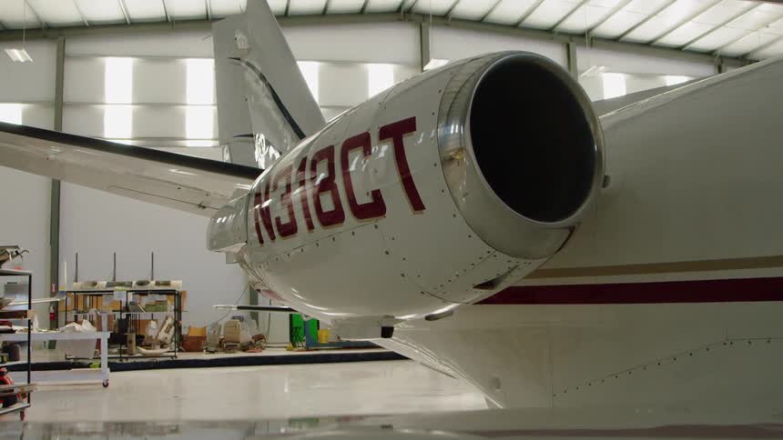 A private airplane is sitting idle in a hangar in daylight