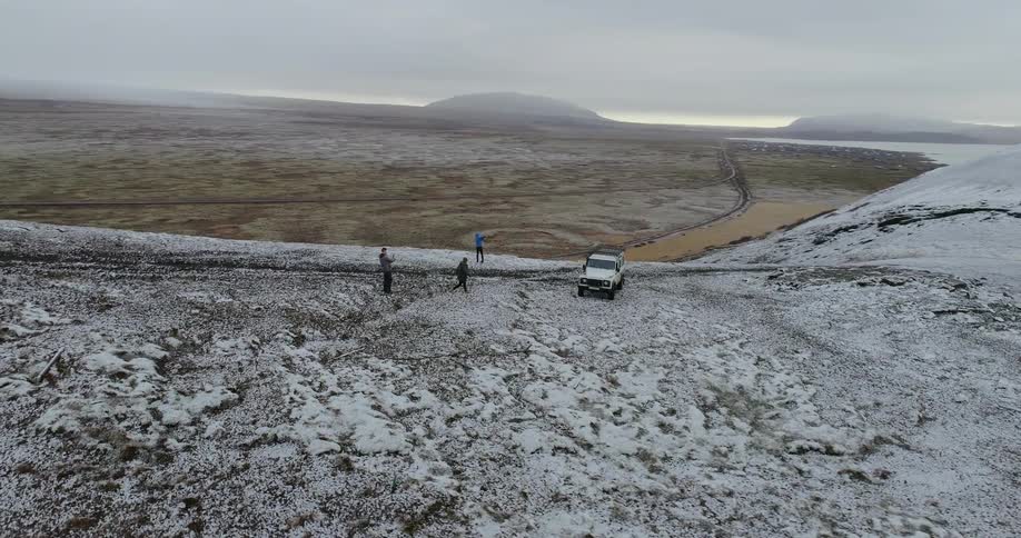 Person runs towards a white vehicle on a snowy hill