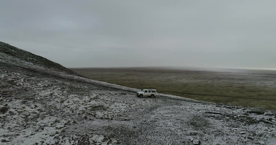 A vehicle is parked on a snowy hillside