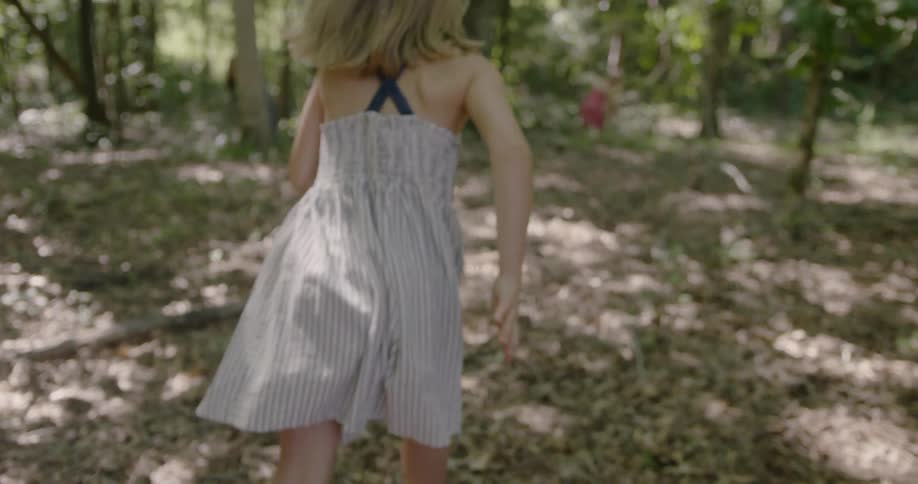 A child uncovers her eyes then runs into the forest