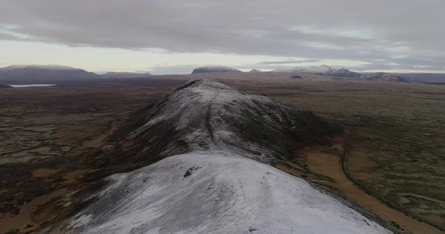 Hills in a barren landscape are dusted with snow