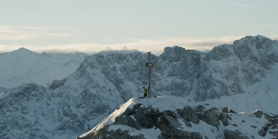 Cross on top of a snowy mountain on a cloudy day