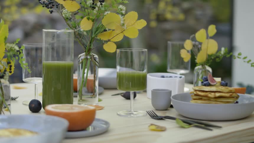 Wind blows plants on a table set with food outside