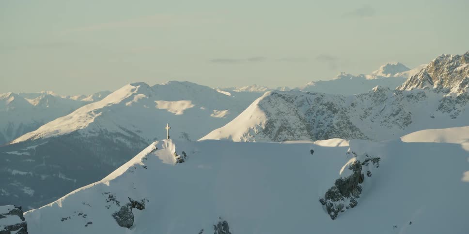 Cross statue on top of snow covered mountain