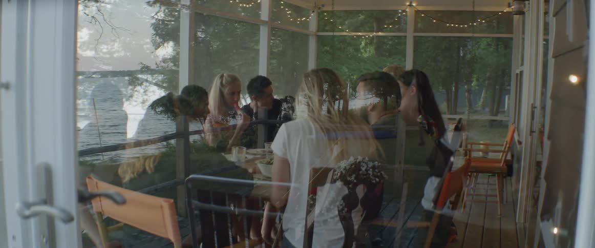 The people inside the porch sit down to a meal together