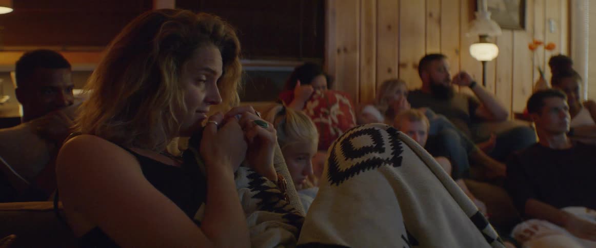 Group of people are sitting in living room watching scary movie
