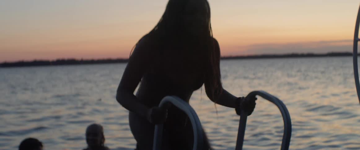 People climb up out of the water at sunset