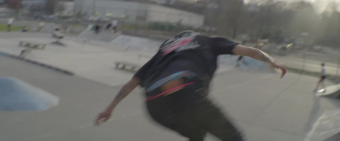 A man riding a skateboard does a twirl and rick off the side of a ramp