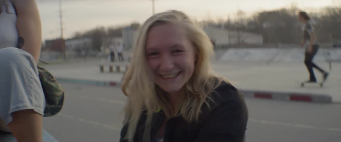 Smiling teenage girl stands at a skatepark