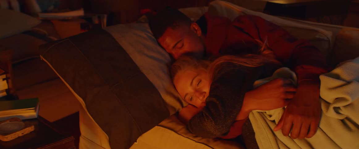 A man hugs a woman as they rest in bed