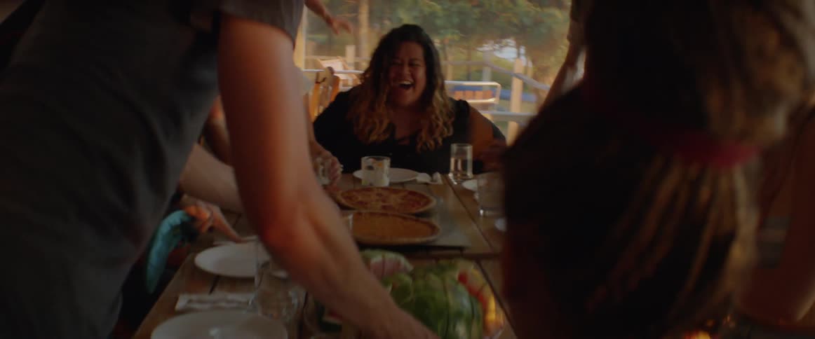 Group of people are having lunch and laughing outside on porch